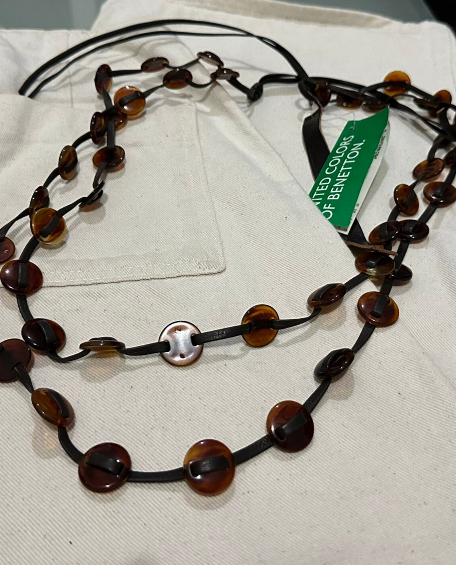 belt with brown and black beads on a white surface with a green tag.