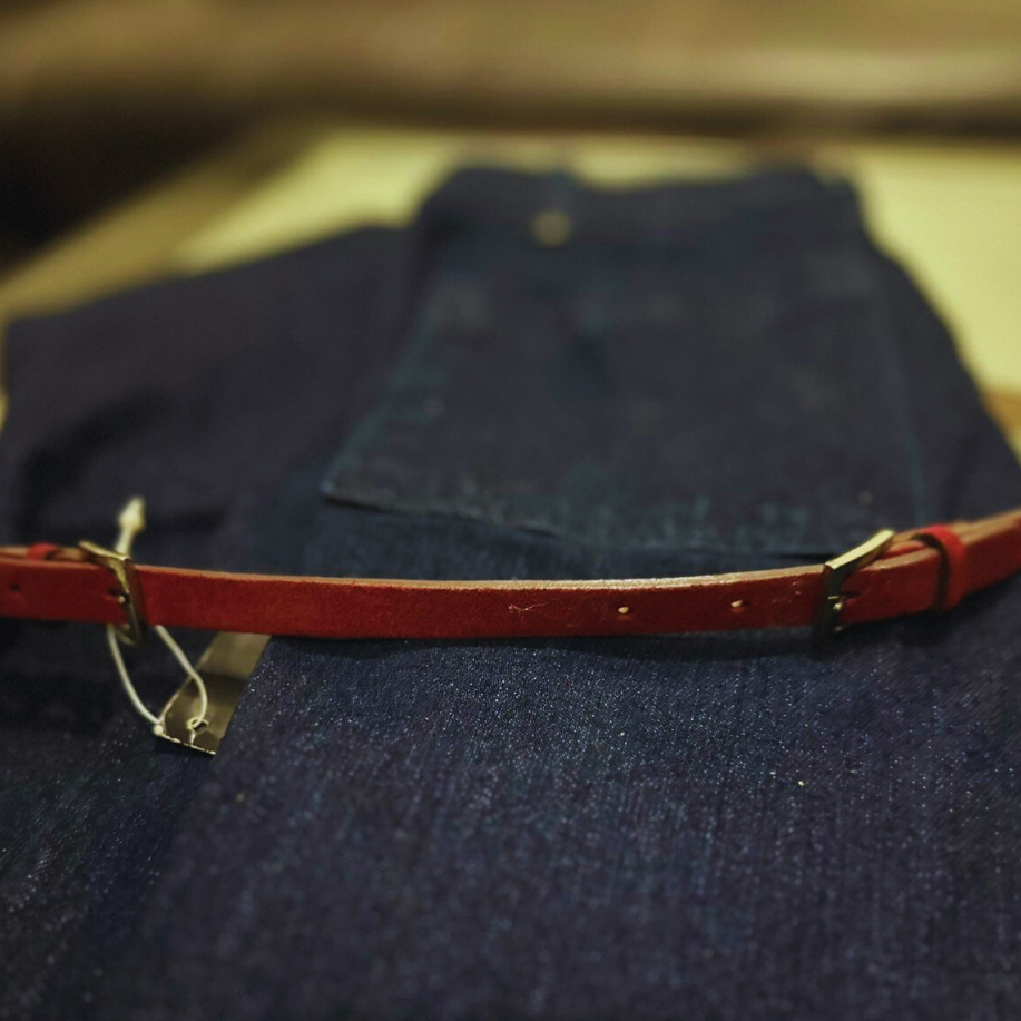 Red leather belt on a dark blue fabric background