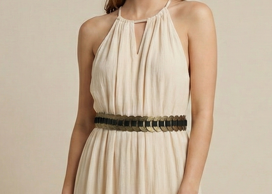 Woman wearing a beige halter neck dress with a black belt on a beige background